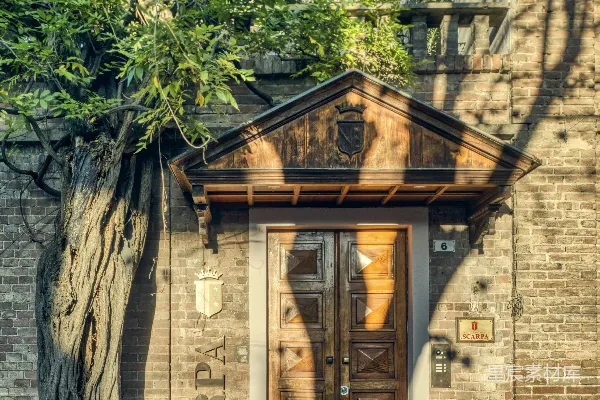 高清摄影 一幢砖砌建筑上有一扇木制双扇门，旁边有一棵树。