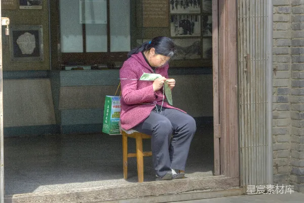 高清摄影 穿着粉红色夹克和蓝色牛仔裤的女人坐在棕色的木椅子上。