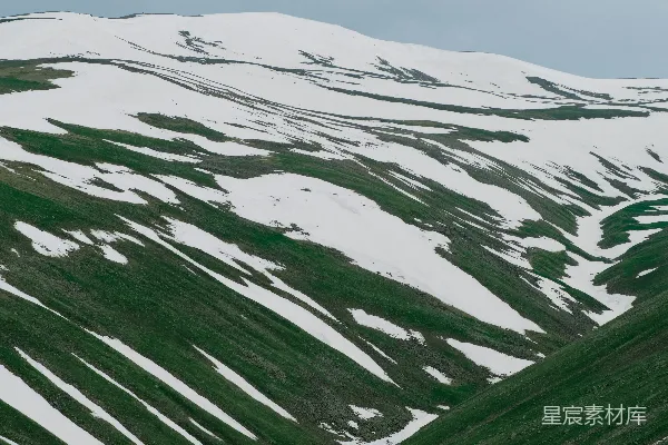 覆盖着白雪的山峦与绿色草地共存