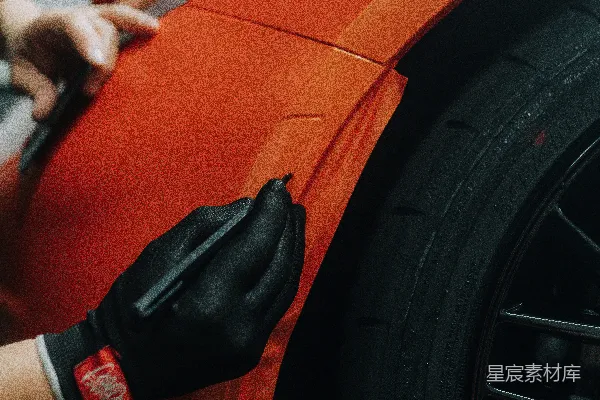 高清摄影 一个男人正在修理一辆橙色的车。