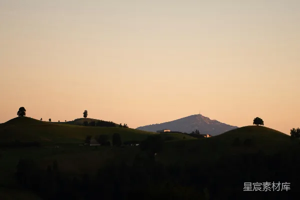 山脚下有树木，背景是高山。