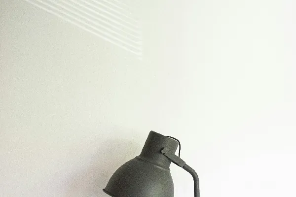 高清摄影 一盏黑色的灯放在白色墙的顶部。