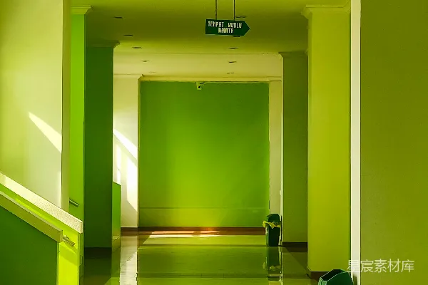 高清摄影 一条长长的走廊，墙壁是绿色的，地上有一个绿色的垃圾桶。