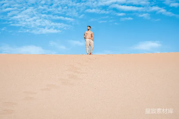 高清摄影 一个男人在蓝天下的沙丘上行走