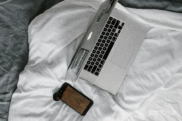 高清摄影 MacBook Pro 放在棕色皮质钱包旁边，放在白色的床上。