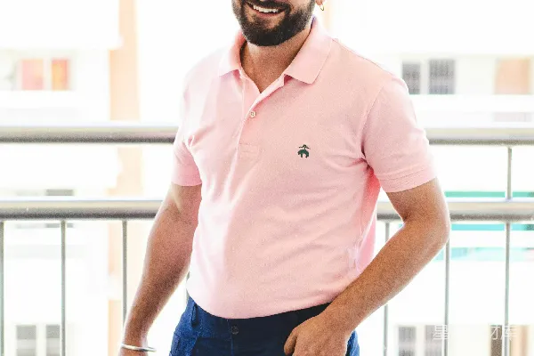 穿粉红色polo衫和蓝色牛仔裤的男人戴着黑色太阳镜