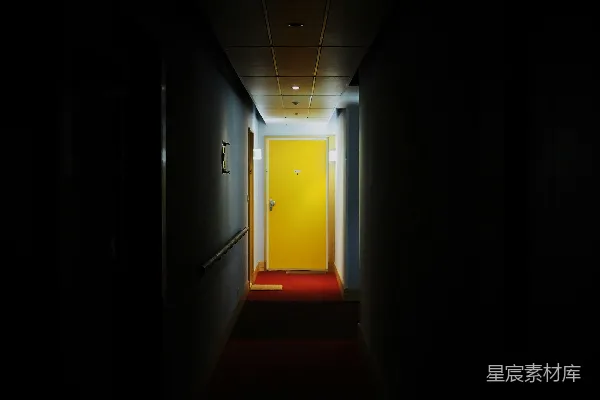 高清摄影 昏暗的走廊，尽头有一扇明亮的黄色门。