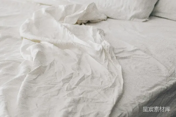 高清摄影 一张皱巴巴的白色床，上面有枕头。