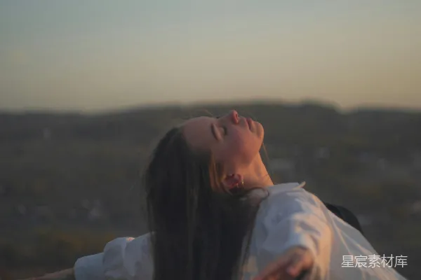 一位女性站在田地里双臂张开
