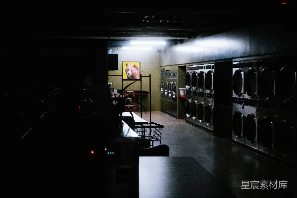 高清摄影 在昏暗的洗衣店中，一排排洗衣机整齐地摆放着。