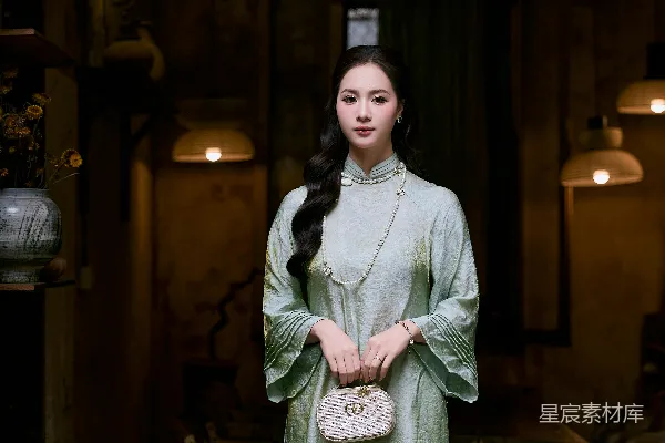 高清摄影 穿着浅绿色的传统连衣裙的女士手里拿着一个钱包。