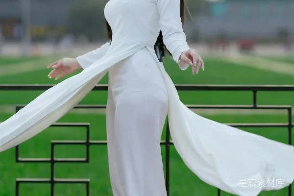 一名女子身穿传统的白色服装站立。