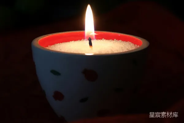 高清摄影 一盏点燃的蜡烛放在装饰性的碗里，碗上有红色的点缀。