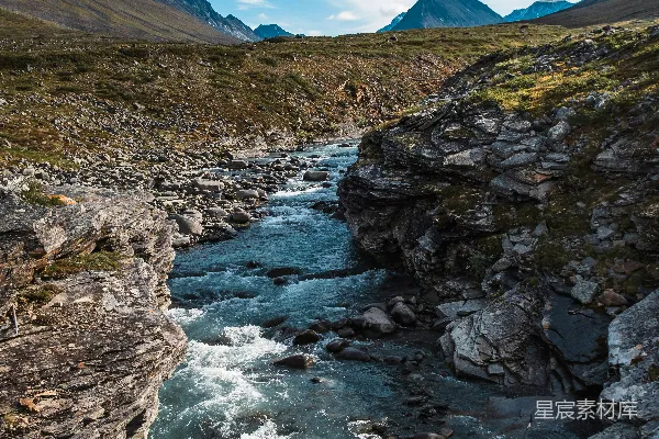 一条河流穿过一片岩石山谷，在蓝天之下流淌。