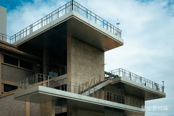 高清摄影 在多云的天空下，一座粗犷的混凝土建筑上有安全摄像头。