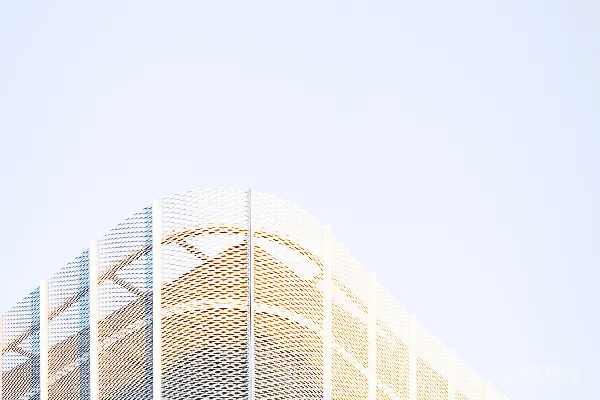 高清摄影 现代建筑的转角，背景是浅色的天空，建筑表面有穿孔设计。