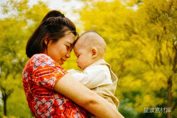孕妇身边抱着婴儿靠近黄色的树木