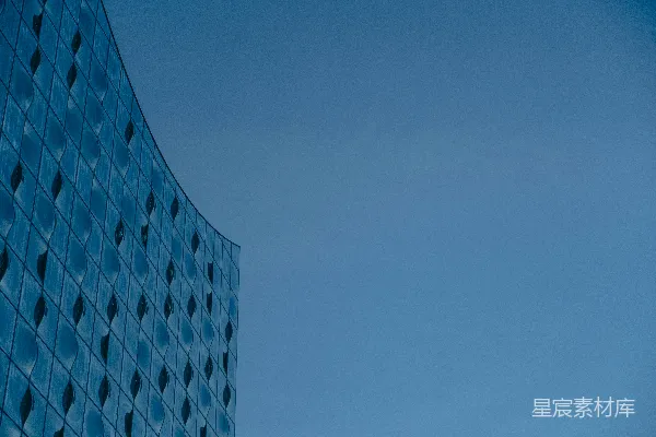高清摄影 弯曲的蓝色玻璃建筑外墙映衬着晴朗的天空。
