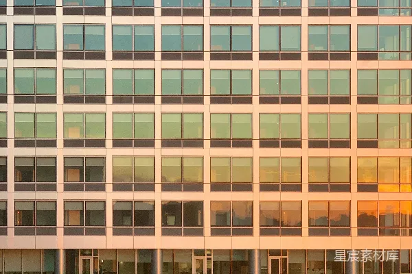 高清摄影 现代建筑外墙上有许多窗户，夕阳的余晖映照在玻璃上。