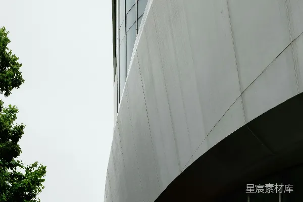 高清摄影 现代化的建筑，有弯曲的白色墙壁和绿色的树木。