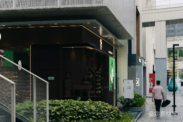 高清摄影 现代建筑外墙，配有绿植，一名男子正在行走。