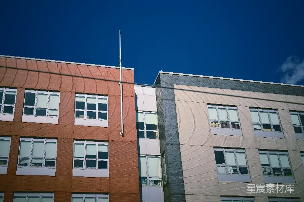 高清摄影 两栋多层建筑在蓝天下的旗杆下。