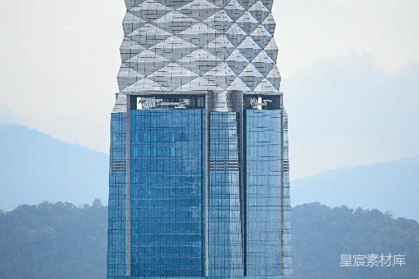高清摄影 一座现代摩天大楼，外墙为蓝色玻璃，顶部呈几何形状。