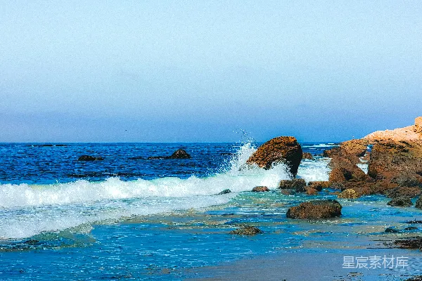 一块岩石嶙峋的海滩，海浪拍打着岩石。