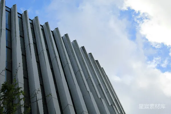 高清摄影 现代建筑的立面，垂直的肋条在多云的天空背景下。