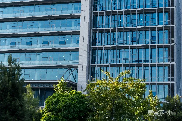 高清摄影 现代玻璃建筑前有绿树。
