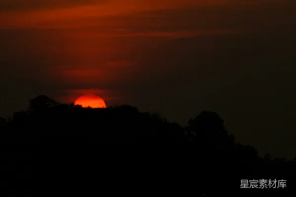 山头的太阳正在落下， surrounded by trees.