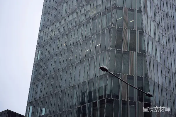 高清摄影 现代玻璃摩天大楼，路灯与灰色的天空相映成趣。