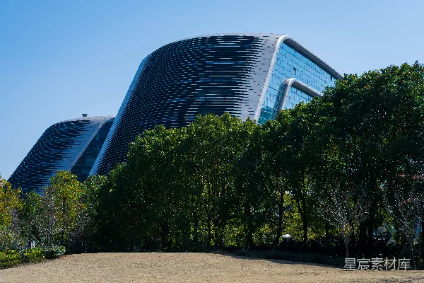 高清摄影 在晴朗的日子里，绿树后是现代化的曲线建筑。