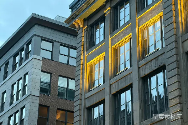 高清摄影 两栋城市建筑，其中一栋被温暖的黄色灯光照亮。