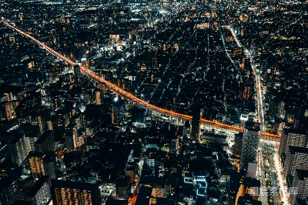 夜晚的城市光彩夺目，有一座突出的弯曲红色大桥。