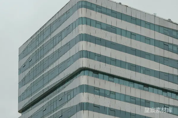 高清摄影 现代建筑，其波浪形条纹立面在灰色天空背景下。