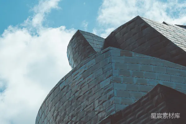 高清摄影 现代建筑，带有弯曲金属立面，映衬在天空中。