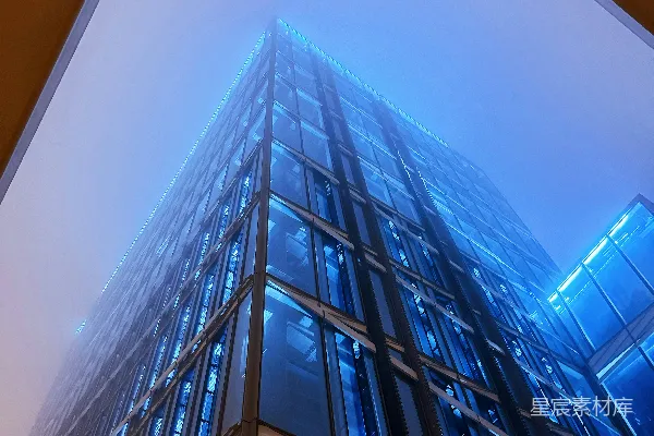 高清摄影 被黄色建筑物环绕的高大的蓝色玻璃建筑在雾中。