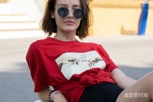 红色和白色圆领针织衫的女人坐在白色的长凳上，穿着黑色的裙子。