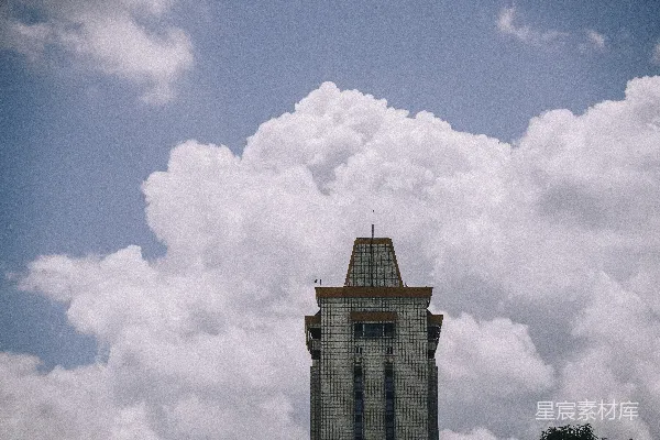 高清摄影 一座高楼矗立在蓬松的白云背景前。