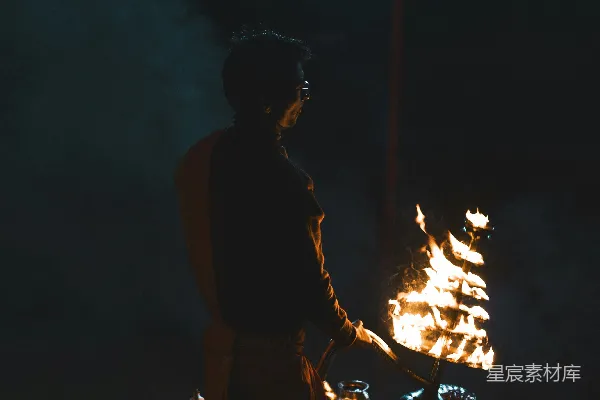 黑色T恤男子站在夜晚近火的地方