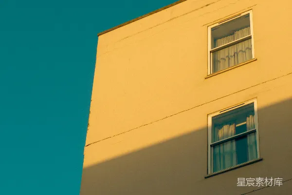 高清摄影 黄色的建筑在充满活力的蓝天中，窗户在上面。