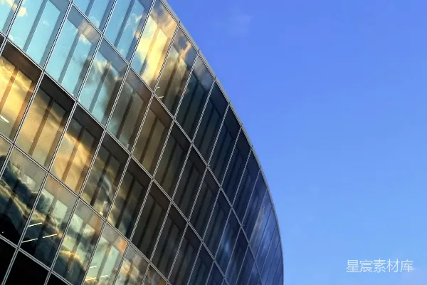 高清摄影 现代玻璃建筑在蓝色天空背景下反射着金色的落日光辉。