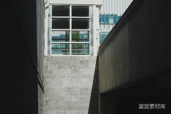 高清摄影 阳光照耀的混凝土小巷通往现代化大楼入口。