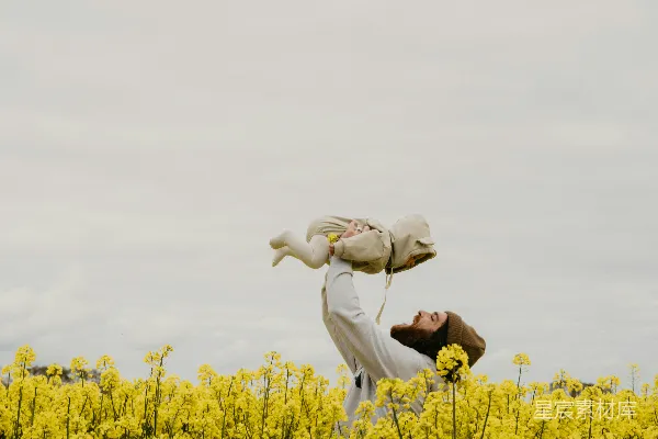 一个人在一丛黄色花朵的田野里抱着一个婴儿。