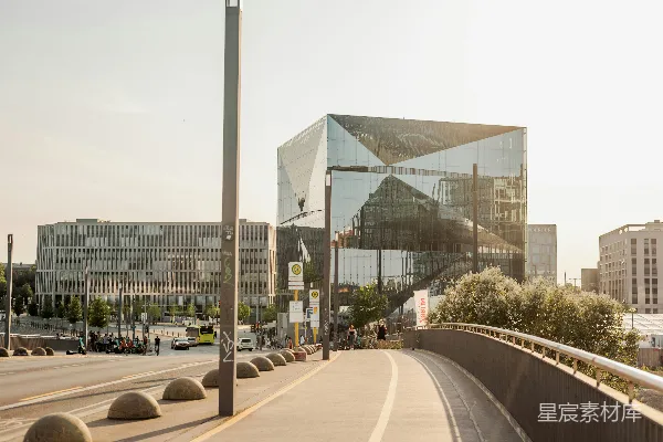 高清摄影 一座现代化的玻璃建筑，位于一座城市中，旁边有一座桥。