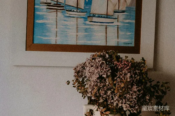 墙上挂着一幅帆船的画，旁边放着一束鲜花。