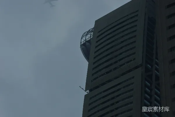 高清摄影 一架飞机在阴天飞过一座高大的建筑物。