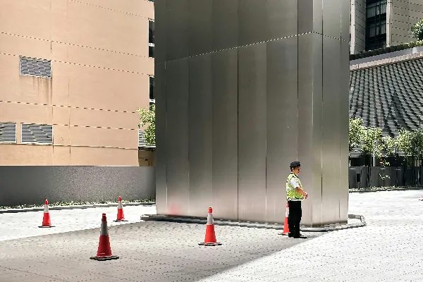 高清摄影 男人站在大型金属结构旁边，旁边有交通锥。