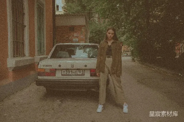 一个女人站在一辆古董车前。